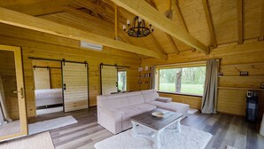 A cozy cabin interior with a large sofa, a dining table, and a chandelier. - Zaga Zaga Sat (Cosmesti)