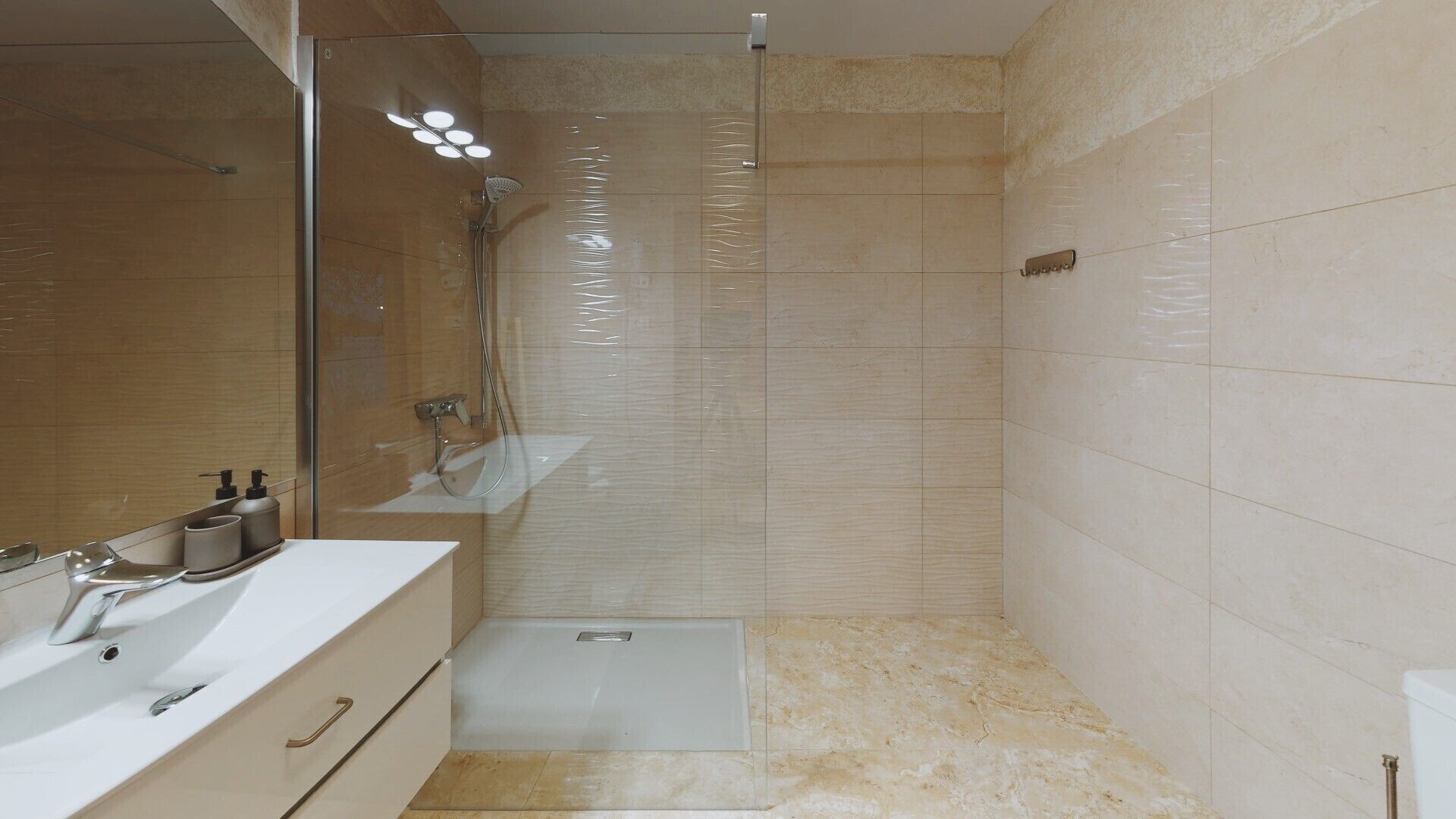 Un baño moderno con cabina de ducha de vidrio, lavabo con espejo y inodoro.