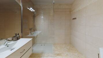 Un baño moderno con cabina de ducha de vidrio, lavabo con espejo y inodoro.