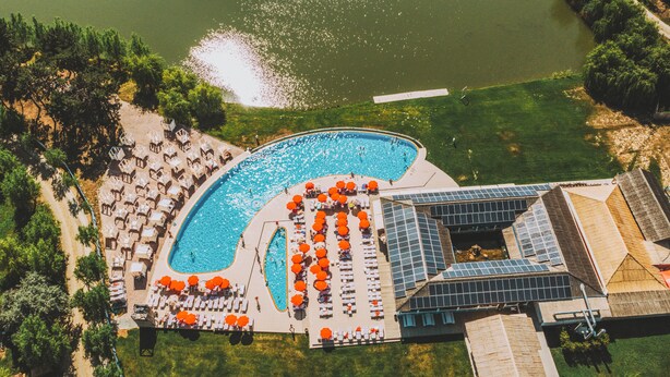 An aerial view of a resort with a large pool, sun loungers, and a separate building with solar panels. - Zaga Zaga Sat (Cosmesti)