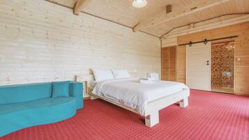 Una habitación de cabaña de madera con una cama, un sofá azul y una alfombra roja.
