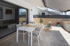 An outdoor patio with a dining table, chairs, a sofa, and a small seating area with cushions.