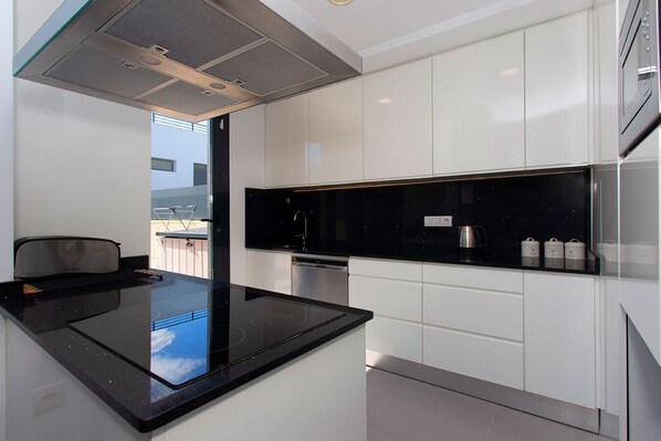 A modern kitchen with a black countertop, white cabinets, and stainless steel appliances.