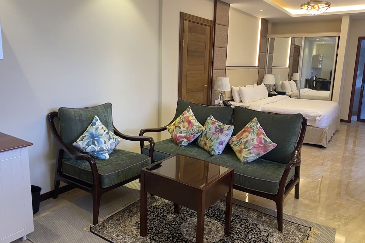 A hotel room with a sofa set, a small table, a bed, and a mirror.