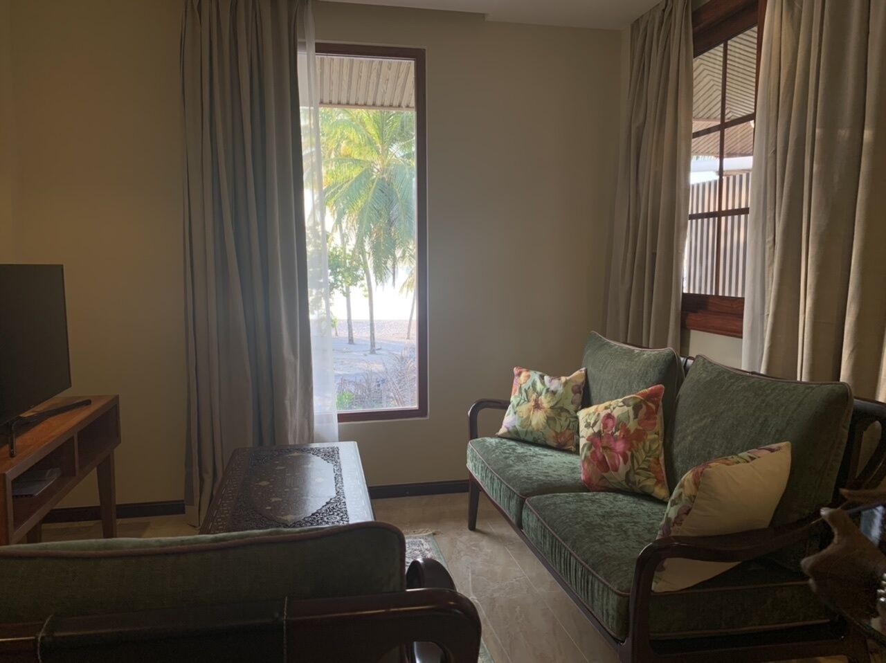 A living room with a sofa, a television, and a window with curtains.