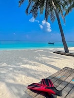Perto da praia, areia branca, espreguiçadeiras, guarda-sóis
