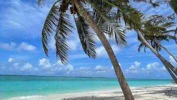 Aan het strand, wit zand, ligstoelen aan het strand, parasols