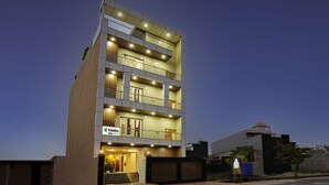 A multi-story hotel with a modern design, featuring balconies on each floor, a visible entrance with a reception area, and a sign indicating the name 'treebo'. - Treebo Grand Vista - 63A (Noida)