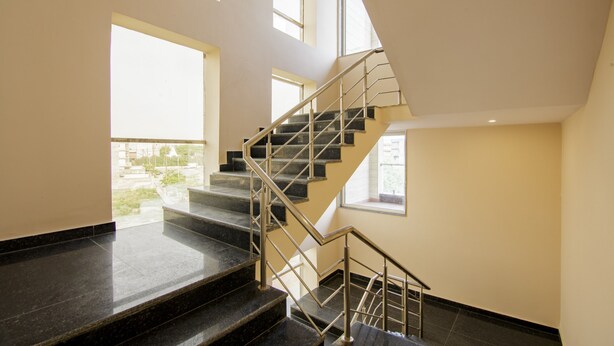 A modern staircase with metal railings and black marble steps, leading to an upper floor. - Treebo Grand Vista - 63A (Noida)