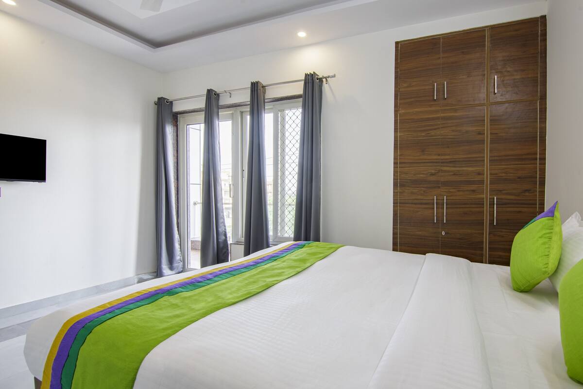 A modern bedroom with a large bed, a wardrobe, and a window with curtains.