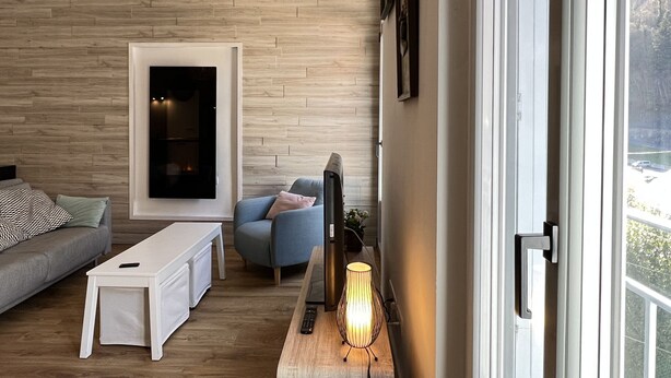 A modern living room with a sofa, a coffee table, a TV, and a lamp. - Haut du village, T2 + alcôve 5p. (Cauterets)