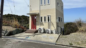 A modern two-story building with a red door, multiple windows, and outdoor air conditioning units. - shirahamakashibessoD-157 (Shirahama)