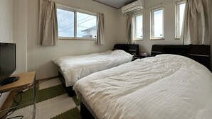 A hotel room with two beds, a desk with a computer, and an air conditioning unit. - shirahamakashibessoD-157 (Shirahama)