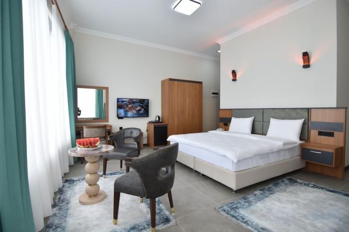 A hotel room with a bed, a desk, a chair, a television, and a wardrobe.