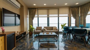 A modern living room with a sofa, coffee table, and dining area. - Fevzi Hoca Hotel (Akçaabat)