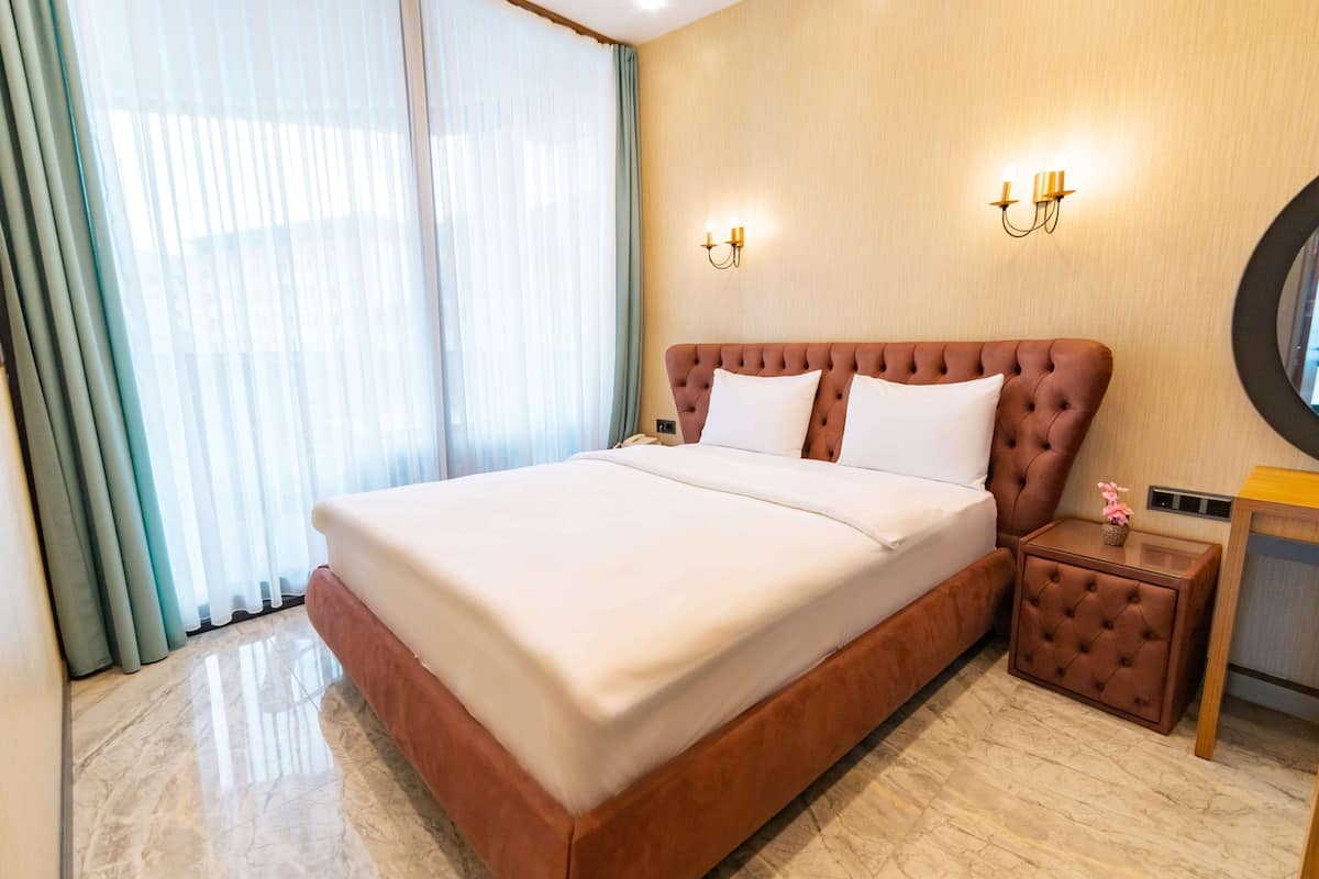 Quarto de hotel com uma cama grande, uma mesa de cabeceira e um espelho.