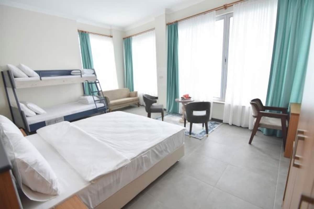A hotel room with a single bed, a bunk bed, a desk, and a chair.