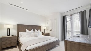 Une chambre d’hôtel avec un grand lit, deux tables de chevet avec des lampes, un bureau et une fenêtre avec des rideaux.
