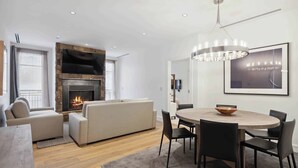 Un salon moderne avec une cheminée, un canapé, une table à manger avec des chaises et un lustre.
