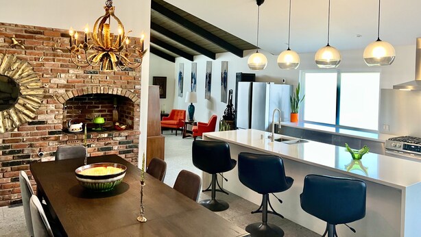 A modern kitchen with a brick fireplace, a dining area with a wooden table, and a bar area with bar stools. - Four king size bedrooms with 5 bathrooms and a pool with a view of Mt. Shasta (Redding)