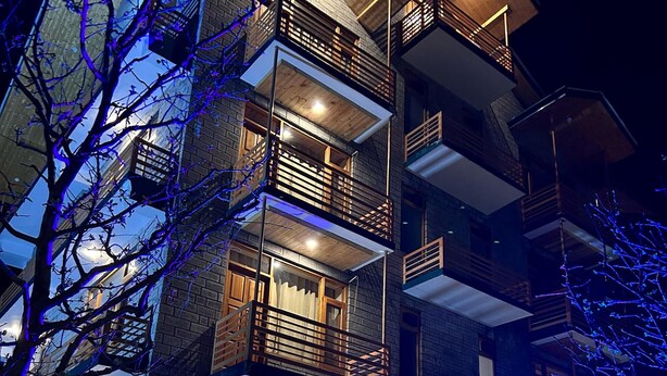 Un edificio de varios pisos con balcones, ventanas amplias y un comedor a la vista.