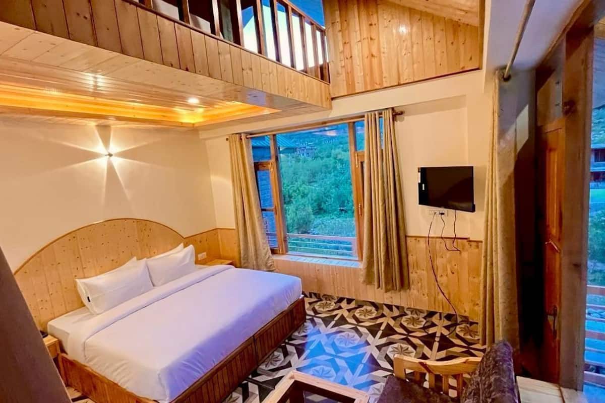 Une chambre avec un lit en bois, une petite table et un téléviseur fixé au mur.