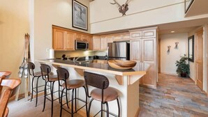 Une cuisine moderne avec un îlot central, des tabourets de bar et une tête de cerf fixée au mur.