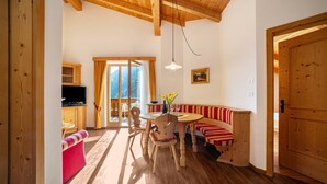 A wooden interior with a dining table, chairs, a bench, and a television. - Apartment 'Obermoarhof Ifinger' with Mountain View, Shared Garden and Wi-Fi (Lagundo)