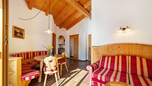 A wooden interior with a dining area, a sofa, and a kitchen in the background. - Apartment 'Obermoarhof Ifinger' with Mountain View, Shared Garden and Wi-Fi (Lagundo)