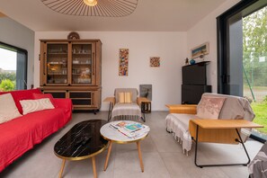 Una sala de estar con un sofá rojo, una mesa de centro negra, un aparador de madera y una chimenea.