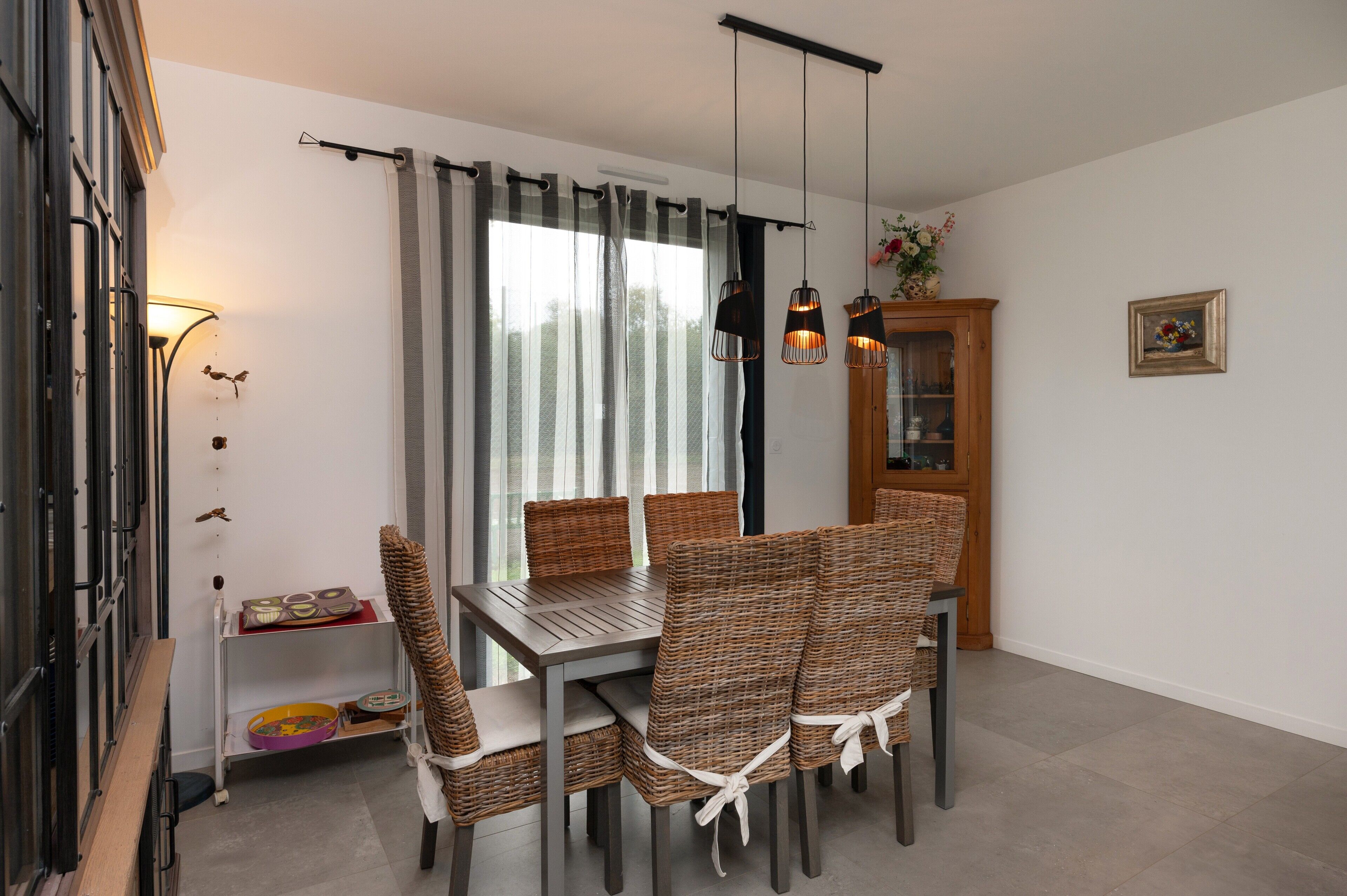 Un espace repas comprenant une table, des chaises, un buffet et un luminaire fixé au mur.