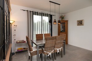 A dining area with a table, chairs, a cabinet, and a wall-mounted light fixture.