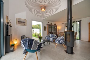 A modern living room with a fireplace, comfortable seating, and a large window.