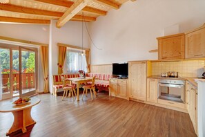 A wooden interior with a dining area, a television, and a kitchen. - Apartment 'Obermoarhof Hirzer' with Mountain View, Shared Garden and Wi-Fi (Lagundo)