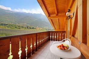 A wooden balcony with a table and chairs, a decorative light fixture, and a view of mountains. - Apartment 'Obermoarhof Hirzer' with Mountain View, Shared Garden and Wi-Fi (Lagundo)