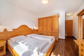 Une chambre à coucher avec un lit en bois, des tables de chevet, une armoire et une commode en bois.