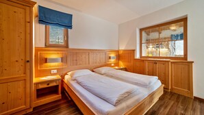 Quarto de madeira com cama, mesas de cabeceira e janela com vista.