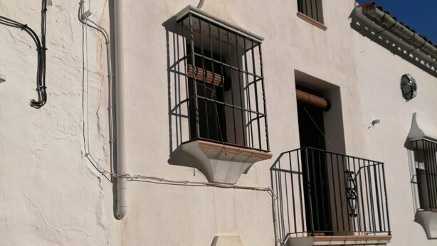 Un immeuble à deux étages doté de balcons, d’une entrée carrelée et de plantes en pot.