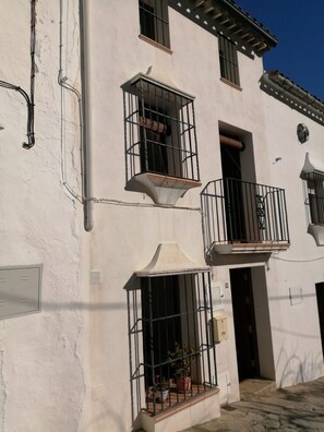 Un immeuble à deux étages doté de balcons, d’une entrée carrelée et de plantes en pot.