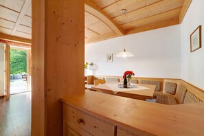 A wooden interior with a dining area, bench seating, and a pendant light.