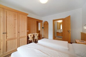 Une chambre à coucher avec un grand lit, une armoire en bois et un petit bureau avec des chaises.
