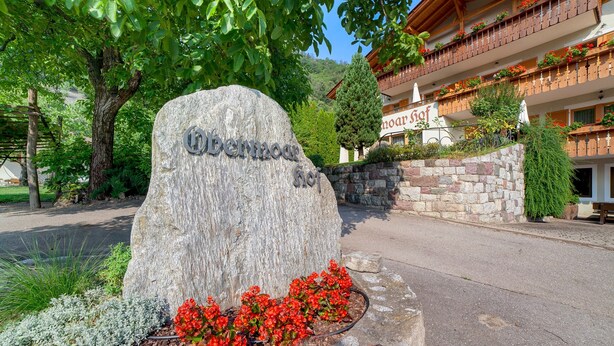 A stone sign with 'Obermoar' inscribed, a building with balconies, and a tree in the foreground. - Apartment 'Obermoarhof Mutspitze' with Mountain View, Shared Garden and Wi-Fi (Lagundo)