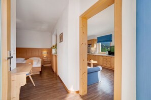 Een kamer met een bed, een bureau, een eettafeltje en een kitchenette.