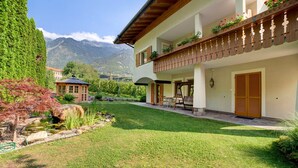 A two-story building with a balcony, a small garden, and a mountain view. - Apartment 'Obermoarhof Mutspitze' with Mountain View, Shared Garden and Wi-Fi (Lagundo)