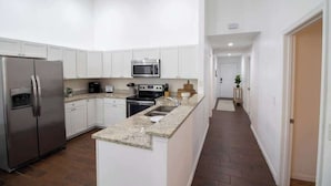 A modern kitchen with white cabinets, stainless steel appliances, and a granite countertop.