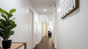 A hallway with a potted plant, a wooden bench, and a wall-mounted sign.