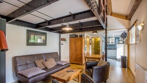 Una sala de estar con sofá, sillas, una mesa de centro y un aparador de madera.