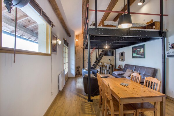 Une pièce de style loft avec une table à manger en bois, un canapé et un lit superposé.