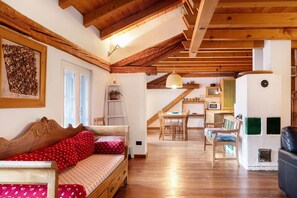 Una habitación acogedora con techo de madera, un sofá, una mesa de comedor y una zona de cocina.