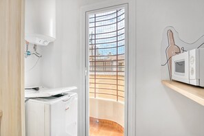 A kitchen with a built-in microwave, a water heater, and a view through a glass door to an outdoor balcony.